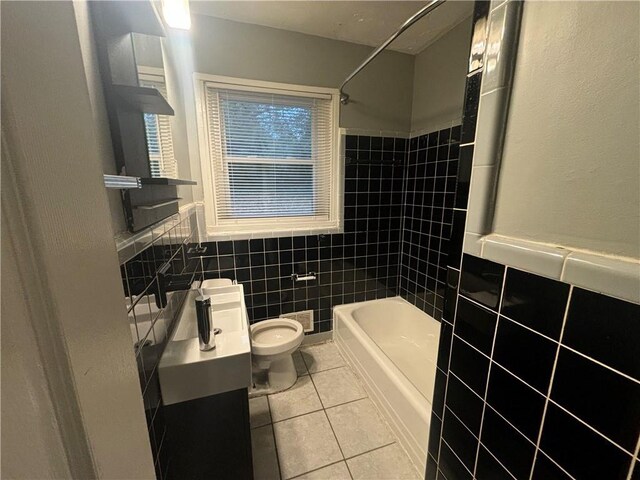 full bathroom with vanity, tile patterned floors, tiled shower / bath, toilet, and tile walls