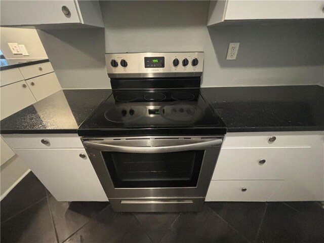 kitchen featuring dark tile patterned flooring, white cabinetry, and stainless steel electric range oven