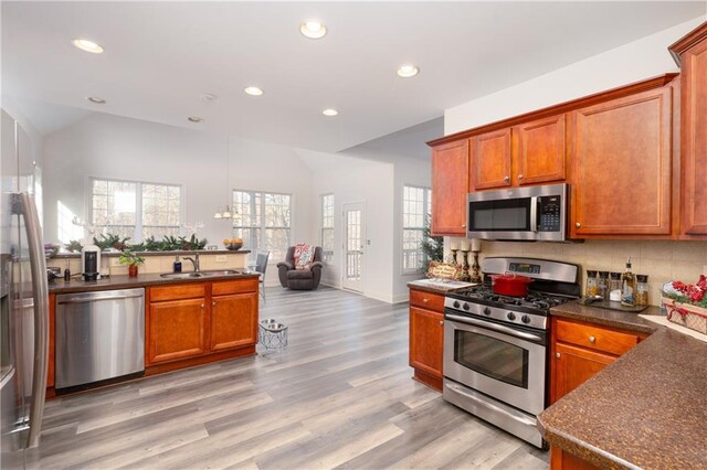 kitchen with decorative backsplash, stainless steel appliances, light hardwood / wood-style floors, and sink