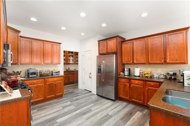 kitchen featuring backsplash, sink, stainless steel refrigerator with ice dispenser, and light hardwood / wood-style flooring