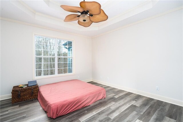 bedroom featuring a raised ceiling, ceiling fan, dark wood-type flooring, and ornamental molding