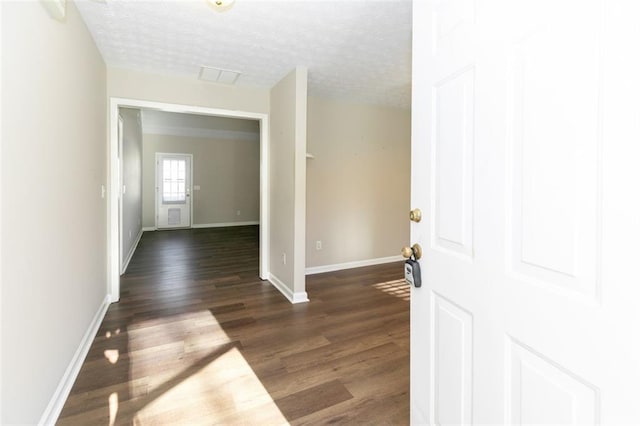 hall featuring dark wood-type flooring and a textured ceiling