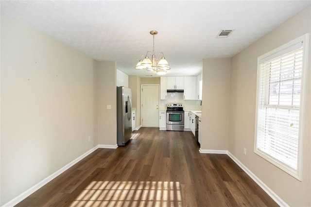 kitchen featuring pendant lighting, white cabinets, appliances with stainless steel finishes, dark wood-type flooring, and an inviting chandelier