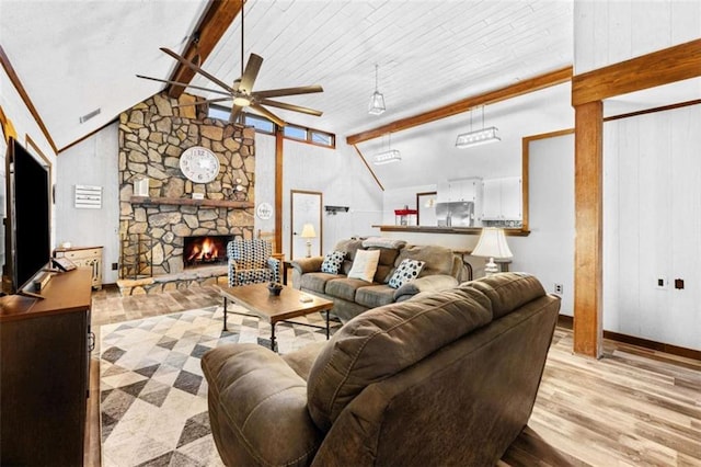 living room with visible vents, a ceiling fan, a fireplace, wood finished floors, and vaulted ceiling with beams