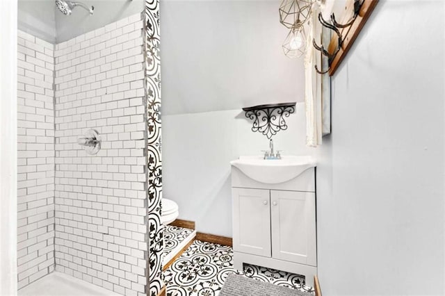 bathroom featuring a tile shower, vanity, and lofted ceiling