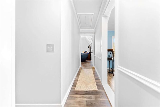 corridor featuring baseboards, attic access, crown molding, and wood finished floors