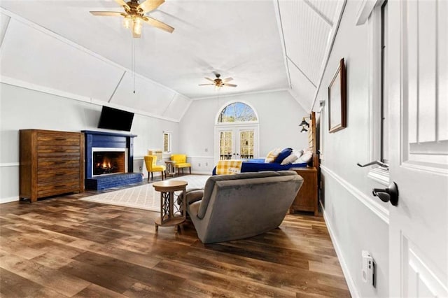 living area featuring wood finished floors, ceiling fan, a fireplace, and vaulted ceiling