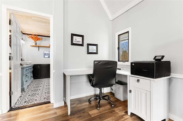 home office with baseboards, light wood-type flooring, and vaulted ceiling