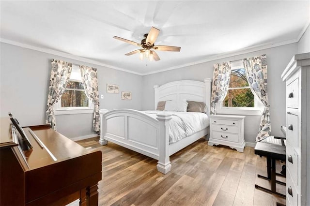 bedroom featuring light wood-style flooring, crown molding, baseboards, and a ceiling fan