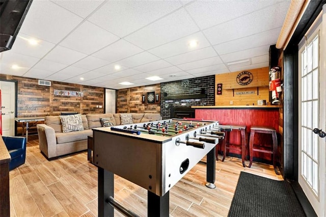 playroom with wooden walls, visible vents, a dry bar, and wood finished floors