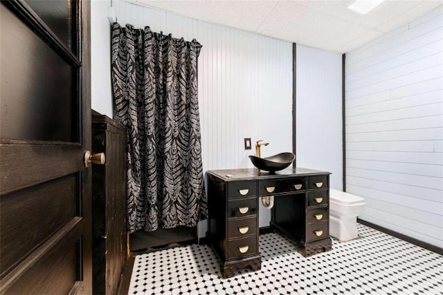 bathroom with wood walls, vanity, and toilet