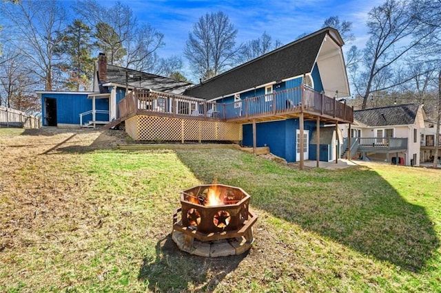 back of house with a yard, a deck, a fire pit, and a chimney