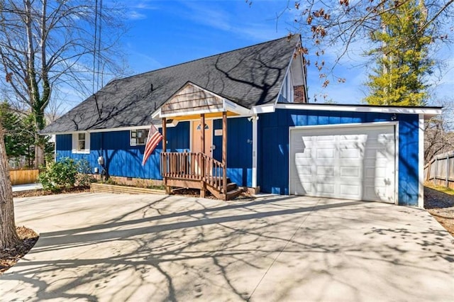 view of front facade featuring concrete driveway, a shingled roof, fence, and an attached garage