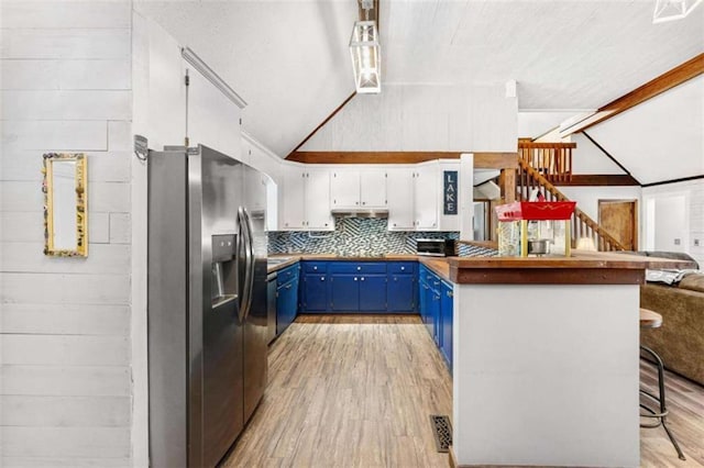 kitchen featuring stainless steel fridge, a peninsula, blue cabinets, light wood-style floors, and vaulted ceiling with beams