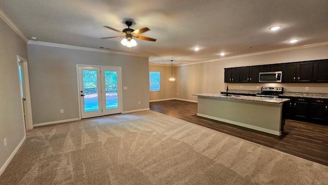 kitchen with appliances with stainless steel finishes, decorative light fixtures, an island with sink, sink, and light stone counters