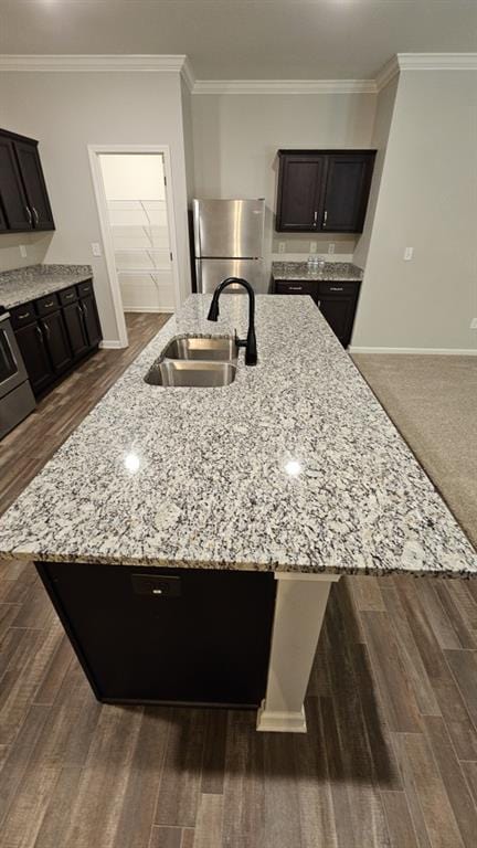 kitchen with stainless steel fridge, light stone countertops, sink, and dark brown cabinets