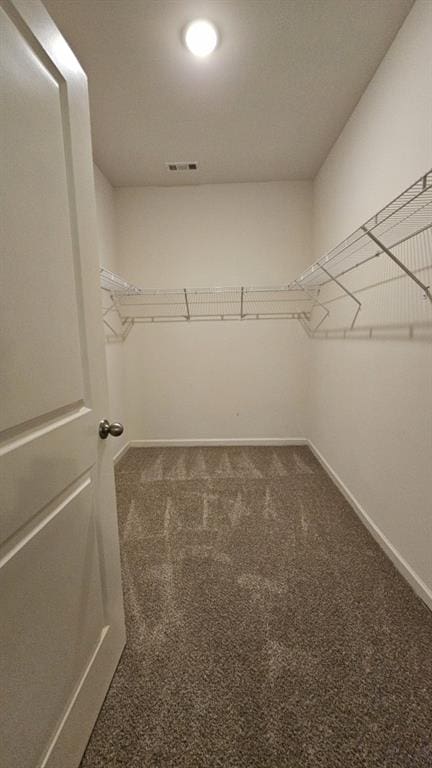 spacious closet with dark colored carpet