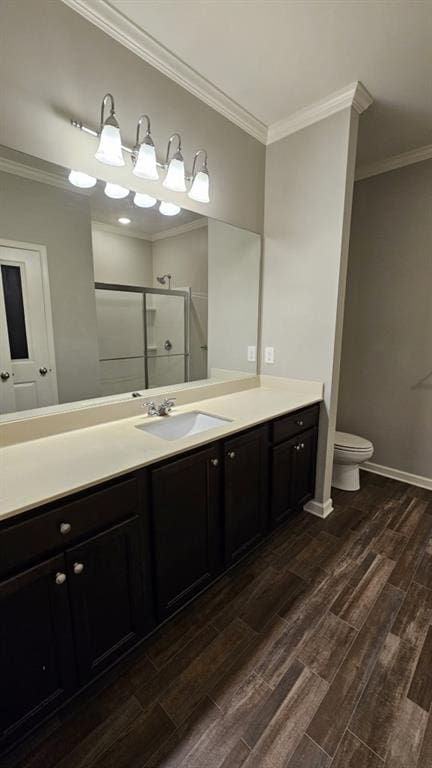 bathroom with an enclosed shower, vanity, ornamental molding, and toilet