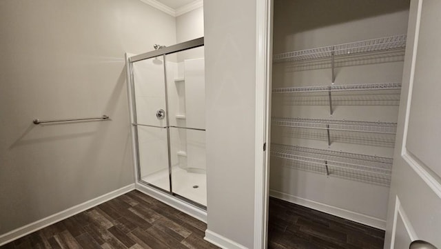 bathroom with hardwood / wood-style flooring, crown molding, and a shower with shower door