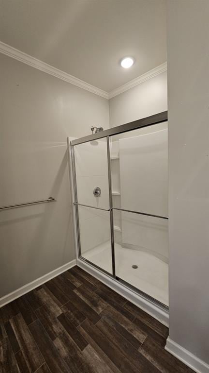 bathroom featuring a shower with door, wood-type flooring, and crown molding