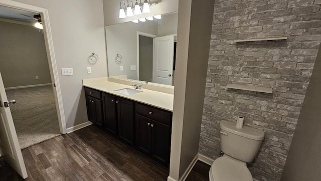 bathroom with brick wall, wood-type flooring, toilet, and vanity