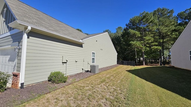 view of side of property featuring a garage, a lawn, and central air condition unit