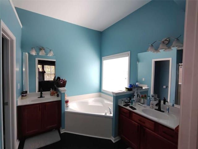 bathroom with two vanities, a sink, and a garden tub