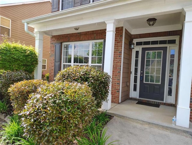 doorway to property featuring covered porch and brick siding