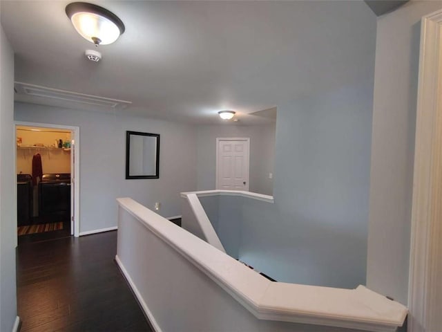 corridor featuring baseboards, attic access, dark wood-style flooring, and an upstairs landing