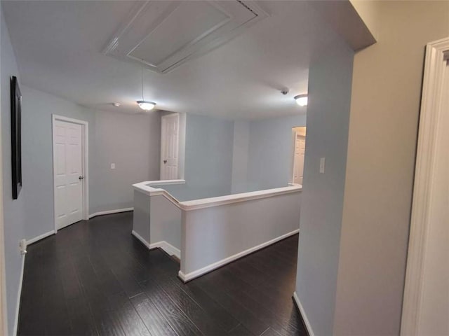 hall with baseboards, attic access, dark wood-style floors, and an upstairs landing