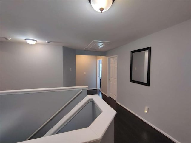corridor with baseboards, attic access, and dark wood-style flooring