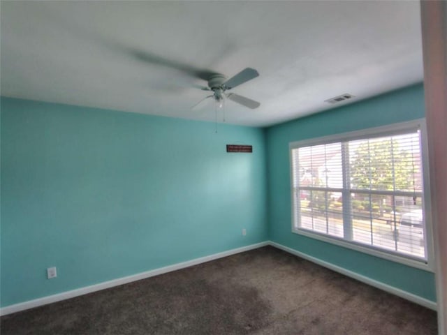 unfurnished room with a ceiling fan, baseboards, visible vents, and dark colored carpet