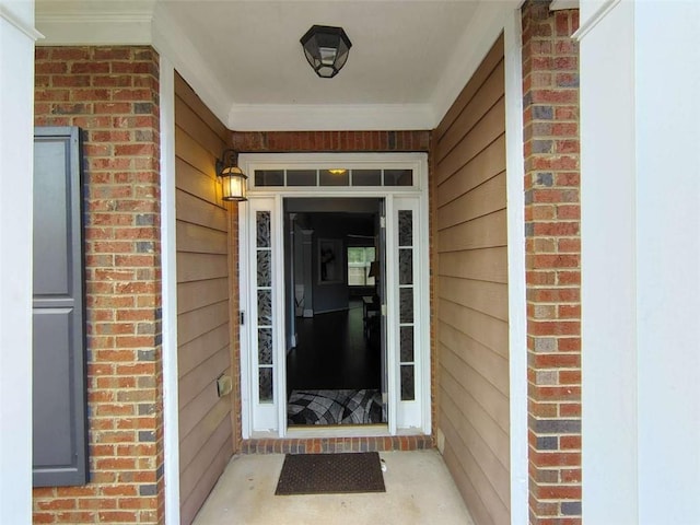 view of exterior entry with a porch and brick siding