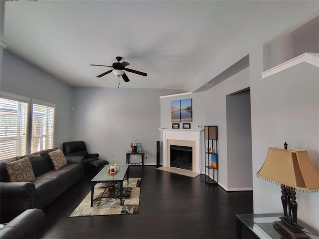 living room featuring a ceiling fan, baseboards, a fireplace with flush hearth, and dark wood-style floors