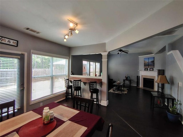 dining room with ceiling fan, a fireplace, baseboards, ornate columns, and visible vents