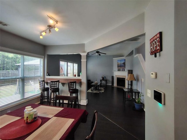 dining area with a fireplace, a ceiling fan, baseboards, decorative columns, and visible vents