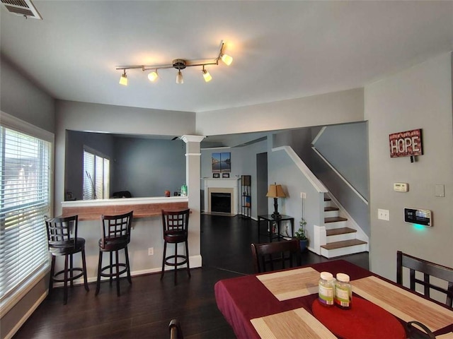 dining space with a fireplace, dark wood finished floors, baseboards, visible vents, and stairway