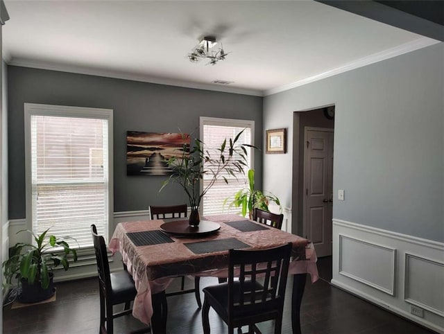 dining area with ornamental molding, wainscoting, and dark wood-style flooring