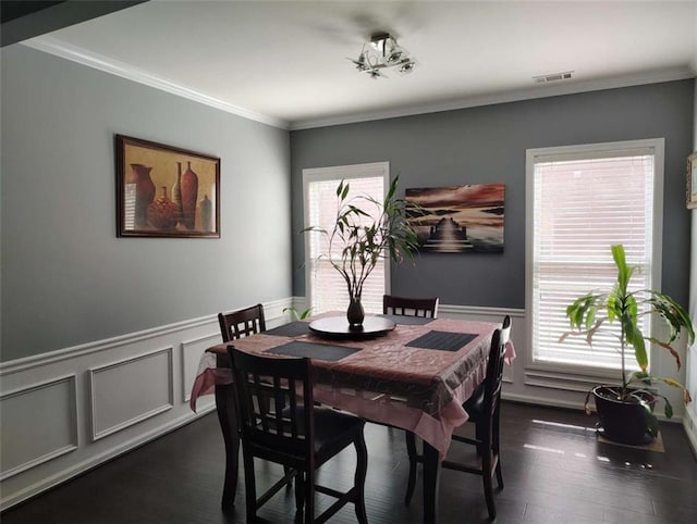 dining space featuring visible vents, wainscoting, crown molding, and dark wood-style floors