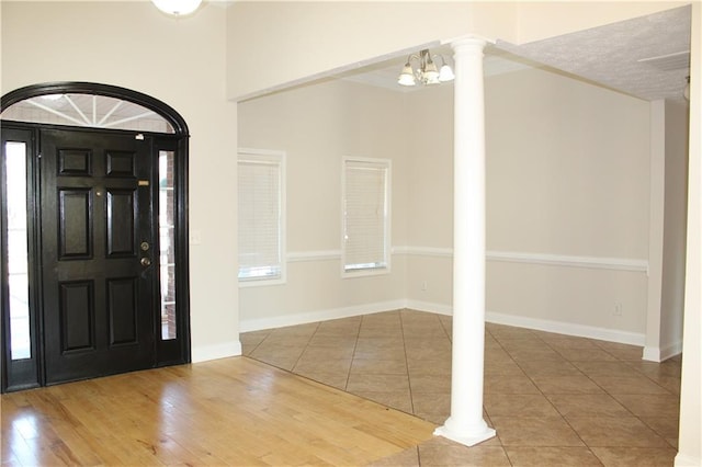 foyer featuring hardwood / wood-style floors, decorative columns, and a chandelier