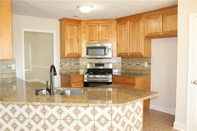 kitchen with sink, light stone countertops, tasteful backsplash, kitchen peninsula, and stainless steel appliances