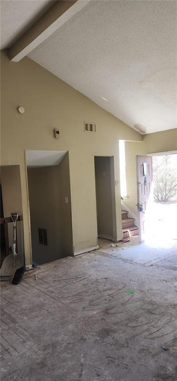 interior space with vaulted ceiling with beams and a textured ceiling