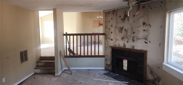 unfurnished living room featuring a tiled fireplace and a textured ceiling