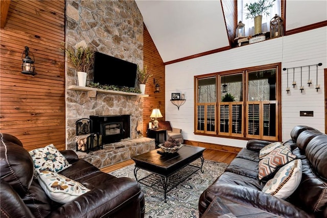 living area with wood walls, wood finished floors, high vaulted ceiling, and a stone fireplace