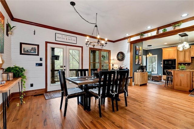 dining room featuring ornamental molding, french doors, light wood finished floors, a notable chandelier, and baseboards