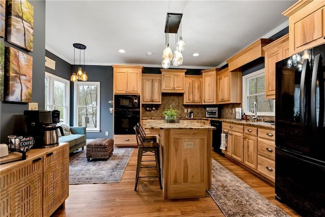 kitchen featuring a notable chandelier, light wood-type flooring, light stone counters, black appliances, and a sink