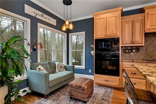 interior space featuring an inviting chandelier, light stone countertops, light wood-style flooring, ornamental molding, and black appliances