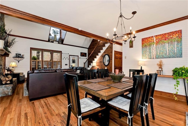 dining area featuring light wood finished floors, a notable chandelier, a high ceiling, and wooden walls