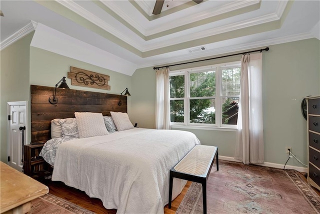 bedroom with baseboards, ornamental molding, visible vents, a tray ceiling, and wood finished floors