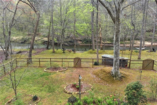 view of yard with a wooded view, fence, and a gate